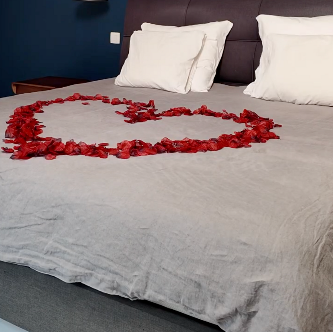 Cœur en pétales de rose rouges sur un lit blanc — décoration romantique Boxe Deco